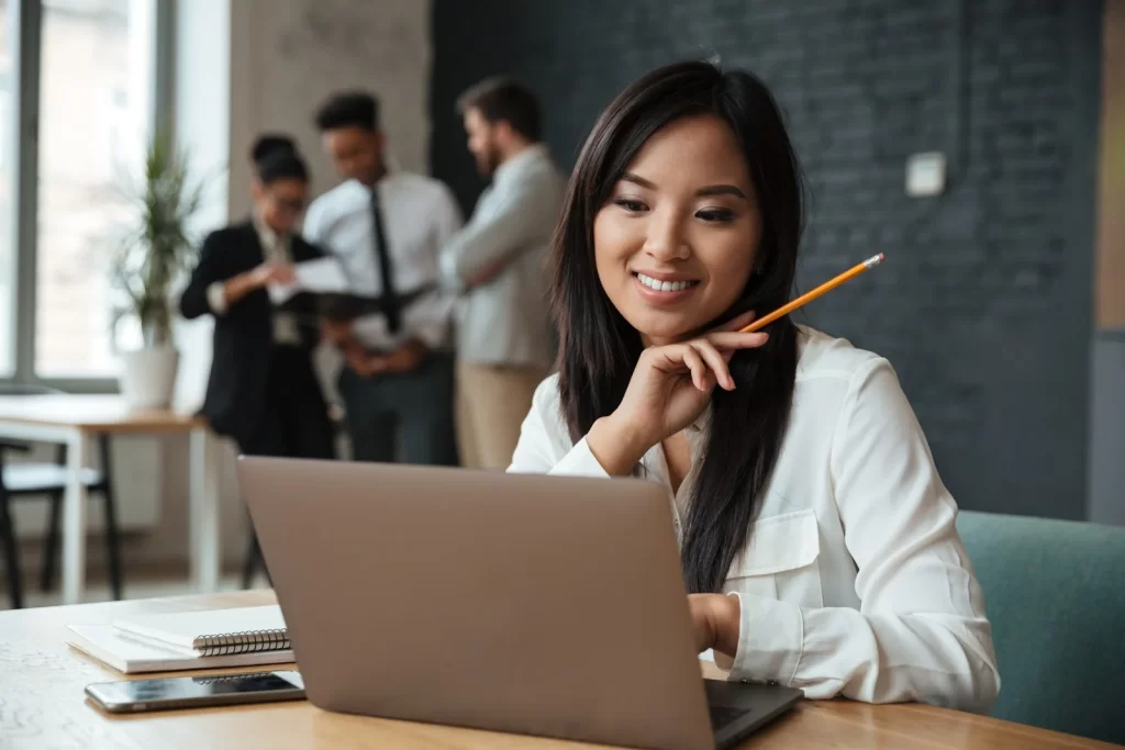 woman holding pencil infront of laptop
